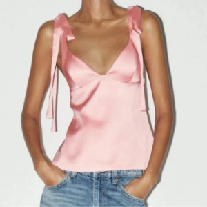 Rosa sidenlinne med knytband - Supersöt ljusrosa linnetopp i glansigt sidenmaterial med v-ringning och breda axelband som knyts till rosetter på axlarna. Perfekt att styla med jeans eller kjol för en trendig look. Andvänd 1 gång!