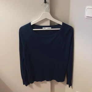 Mörkblå långärmad tröja från Zara - En stilren mörkblå långärmad tröja från Zara i storlek S. Tröjan har rund halsringning och är tillverkad i ett mjukt, tunt material som känns skönt mot huden. Perfekt för lager-på-lager och enkel att matcha med jeans eller kjol.