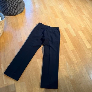 Miu Miu kostymbyxor  - Eleganta, mörkblå byxor med en klassisk design. Byxorna har en tidlös stil som passar både till vardags och mer formella tillfällen.