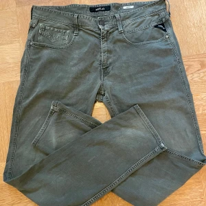 Jeans Replay Anbass - Jeans från Replay i modell anbass.                Storlek W34 L32. Byxorna är lite grå grön aktiga men är snygga. Skick 7/10. Hör av er vid minsta fundering😊
