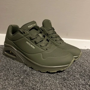 Olivgröna sneakers från Skechers - Snygga olivgröna sneakers från Skechers med chunky sula och luftbubbla i hälen. Skorna har snörning, perforerade detaljer och är tillverkade i syntetmaterial med gummisula. Perfekta för dig som gillar streetstyle och vill ha bekväma skor med cool look. Skorna är aldrig använda 