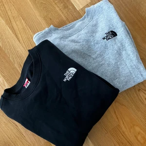 The North Face tröjor - Två stilrena crewneck-tröjor från The North Face i svart och ljusgrått. Klassisk passform med rund hals, ribbade muddar och diskret logga broderad på bröstet. Unisex passform, storlek S dam motsvarande storlek XS herr. 100kr styck
