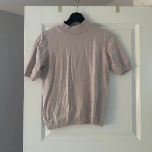 Rosa stickad topp från Stockh LM - Snygg rosa stickad topp från Stockh LM med korta ärmar och hög ribbad krage. Enkel och stilren design som passar till många olika looks.