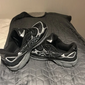 Svarta ASICS GEL sneakers strl 42,5 - Säljer ett par svarta och silverfärgade ASICS GEL skor. Säljer dom pågrund av att dom är för små för mig. Jag har sko boxen kvar.