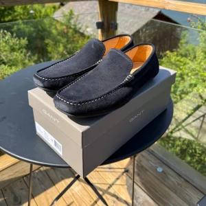 Loafers från Gant i storlek 42 - Ett par loafers från Gant i storlek 42. De är tillverkade av mocka och är i nyskick.   Modellen heter McBay.   Nypris: 1799 kr Mitt pris: 700 kr  Tveka inte på att höra av dig vid minsta fundering!