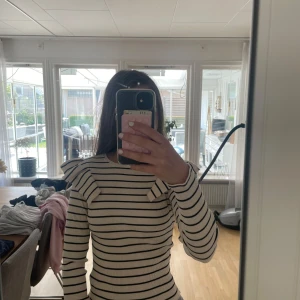 Randig ribbad tröja med volang Zara - Supersnygg ribbad tröja från Zara i vitt med svarta ränder. Tröjan har långa ärmar och coola volangdetaljer på axlarna som ger en trendig look. Perfekt för dig som gillar stilrena men ändå unika plagg.