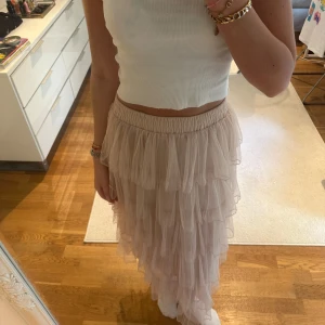 Ljusrosa volangkjol i mesh - Supersöt långkjol i ljusrosa mesh med flera lager volanger. Kjolen har resår i midjan för skön passform och är perfekt. Från okänt märke 