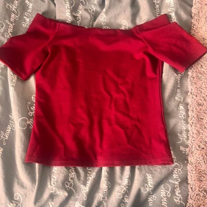 Röd offshoulder topp - Snygg röd offshoulder topp med korta ärmar. Enkel och stilren design som passar perfekt till jeans eller kjol. Mjuk och stretchig känsla, vilket gör den superbekväm att bära. Perfekt för dig som vill ha en trendig och färgstark look. Angänd en gång