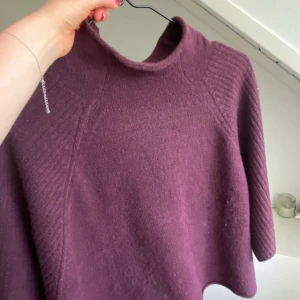 Mörklila stickad tröja Samsa Collection - Mysig mörklila stickad tröja från Samsa Collection med hög hals och trekvartsärmar. Tröjan har en loose passform och ribbade detaljer längs axlar och ärmar. Perfekt mys tröja! 