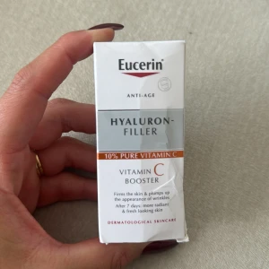 Eucerin Hyaluron-Filler Vitamin C Booster - Eucerin Hyaluron-Filler Vitamin C Booster är en ansiktsprodukt med 10% ren C-vitamin och hyaluronsyra. Den kommer i en vit och silverfärgad förpackning med orange detaljer. Produkten är framtagen för att ge huden lyster och fyllighet samt minska synligheten av fina linjer.