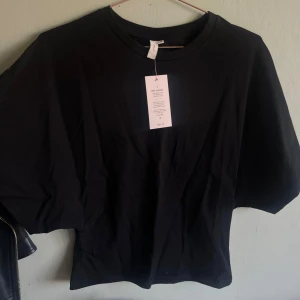Round neck wide sleeve tie  - svart t-shirt från Nelly, super fin och lite mer ”speciell” än en vanlig t shirt. Aldrig använt och prislappen sitter kvar! Säljer pga att den är för liten på mig.