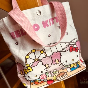 Söt liten tote bag med Hello Kitty-motiv! - Söt liten tote bag i canvas med knäpp-knapp och Hello Kitty-motiv. Mått: 25 x 27 cm. Oanvänd.