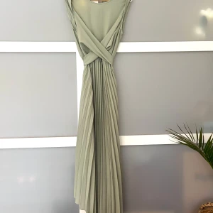 Ljusgrön plisserad långklänning - Superfin ljusgrön långklänning från Shein med plisserad kjol och omlott-detalj i midjan. Ärmlös modell med rund halsringning och knytband i midjan som ger en snygg siluett. Perfekt för sommarens alla tillfällen!