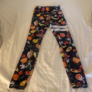 Färgglada leggings från Stronger - Supercoola Leggings från Stronger med mörkblå botten och färgglatt fruktmönster .I storlek XS. Dom är i ett väldigt fint skick 🩷original pris är 799 