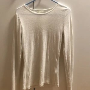 Ribbad vit långärmad tröja H&M - En basic vit långärmad tröja från H&M i ribbad bomull. Tröjan har rund halsringning och sitter figurnära utan att vara för tight. Perfekt att styla med jeans eller kjol för en clean look.