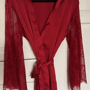 kimono / rock Hunkemöller  - Röd kimono med långa spetsärmar och knytband i midjan. Storlek M/L. Nypris 570:-