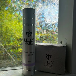 Lilly Nails Hand Cream Lily Flower - Oanvänd!Handkräm från Lilly Nails med doft av Lily Flower, 120 ml. Kommer i en stilren, silverfärgad pumpflaska med lila detalj och svart logga. Perfekt för att hålla händerna mjuka och återfuktade. Svensktillverkad och snygg att ha framme på sminkbordet.