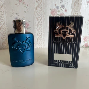 Parfums de Marly Layton  - Lyxig parfym från Parfums de Marly, Layton Royal Essence. Flaskan är matt blå med silverfärgad kork och har två upphöjda hästar och sköld på framsidan. Kommer i elegant svart ask med guldiga detaljer. Volym: 125ml Eau de Parfum.
