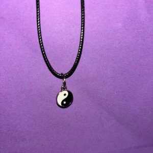 Yin Yang halsband med svart snöre - Coolt halsband med svart snöre och en rund Yin Yang-berlock i svart och vitt. Perfekt accessoar för dig som gillar minimalistisk och stilren design med en touch av österländsk vibe.