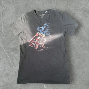 Svart t-shirt från Denim & Supply Ralph Lauren - Svart t-shirt från Denim & Supply Ralph Lauren med coolt tryck av en motorcyklist och nummer 67 på bröstet. T-shirten är i 100% bomull och har klassisk passform med korta ärmar. Perfekt för dig som gillar streetstyle och sportiga vibes. Tröjan är ovanlig och  dem har slutat poroducera denna tröja så den går knappt att få tag i. Priset går att förhandla ner vid snabb köp💯