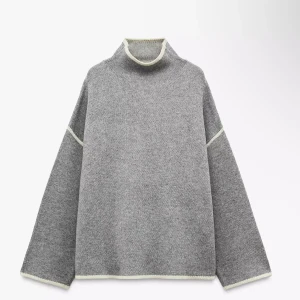 Grå stickad polotröja med kontrastsömmar - Säljer en oversized grå stickad polotröja med vita kontrastsömmar. Tröjan har hög krage, långa ärmar och en loose fit som ger en chill vibe. Perfekt för lager-på-lager och funkar till både jeans och kjol.