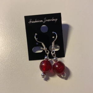 Handgjorda Röda örhängen med glittriga pärlor *Endast 1 Kvar* - Snygga örhängen med stora röda glittriga pärlor och silvriga detaljer. Hängande modell med krok, perfekta för att ge lite extra färg till din look. Enkla att matcha och ger en cool touch till outfiten.