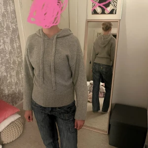 Grå stickad hoodie med huva ZARA - Mysig grå stickad hoodie med huva och snörning. Tröjan har bred ribbad mudd vid midjan och ärmsluten, samt lång ärm. Perfekt för dig som gillar en enkel och stilren look med lite loose fit.