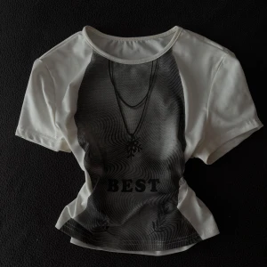 Vit och svart topp med tryck - Cool topp i vitt med svart grafiskt tryck framtill och texten 'BEST'. Rund halsringning och korta ärmar. Trycket har ett smyckesmotiv och vågiga linjer som ger en unik look. Perfekt för dig som gillar streetstyle.