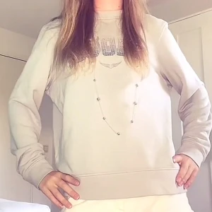 Grå sweatshirt med AMOUR-tryck - Snygg grå sweatshirt med texten AMOUR i glittriga bokstäver framtill. Tröjan har rund halsringning och långa ärmar, perfekt för en chill och avslappnad stil. Passar dig som gillar statement-plagg med lite extra bling.