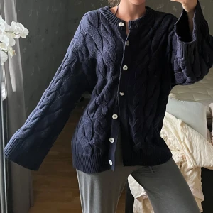 Mörkblå kabelstickad kofta Gina Tricot - Mysig mörkblå kabelstickad kofta från Gina Tricot med stora vita knappar framtill. En knapp är lite sönder men märks knappt