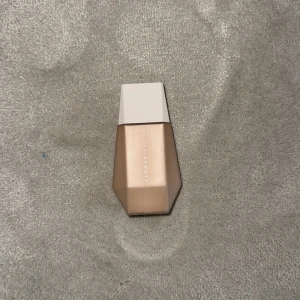 Fenty Beauty foundation beige - Foundation från Fenty Beauty i en snygg beige nyans. Kommer i en modern, geometrisk flaska med vit kork. Perfekt för en jämn och naturlig bas. Passar dig som vill ha en flawless look med lätt till medium täckning i färgen 9.