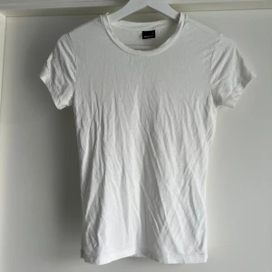 Vit soft touch t-shirt från Gina Tricot - En basic vit t-shirt från Gina Tricot soft touch second skin collectionen i mjuk och stretchig viskosblandning. Modellen är klassisk med rund halsringning och korta ärmar. Perfekt att styla med jeans eller kjol för en clean look.