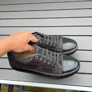 Svarta sneakers från Lanvin i mocka - Snygga svarta sneakers från Lanvin med ovandel i mjuk mocka och glansig lackad tå. Skorna har rund tå, svarta snören och en platt sula. Perfekt för dig som gillar stilrena och exklusiva detaljer i din vardag.