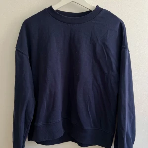 Mörkblå sweatshirt från H&M Divided - Enkel och stilren mörkblå sweatshirt från Divided. Tröjan har rund halsringning, långa ärmar och är gjord i mjuk bomull. Perfekt för en chill och avslappnad look. Passformen är normal och materialet känns skönt mot huden.