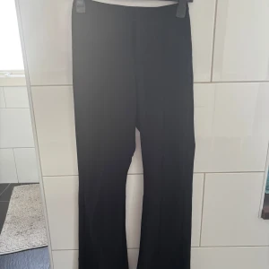 Svarta bootcut kostymbyxor - Snygga svarta kostymbyxor från Gina tricot med bootcut passform. Byxorna har hög midja och raka ben som släpper ut lite nertill för en trendig siluett. Perfekta att styla med sneakers eller boots. Materialet känns mjukt och följsamt. Storlek XS. Köparen står för frakt. Har två stycken likadana. 