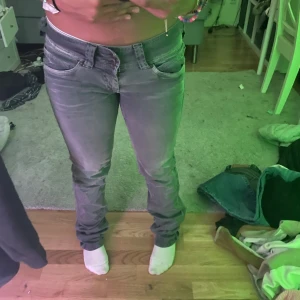 Pepe Grå bootcut jeans med låg midja - Säljer ett par grå jeans med låg midja och bootcut ben. Jeansen har klassisk femficksdesign, bälteshällor och dragkedjegylf. Snygg tvättad look och passar perfekt till en avslappnad stil. Stilig design på bakfickor.