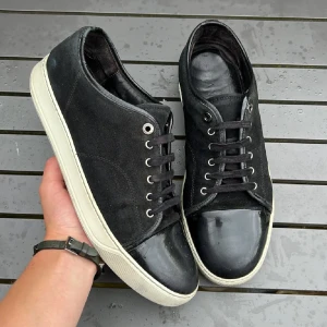  Lanvin med lackad tå - Snygga svarta sneakers från Lanvin med klassisk vit sula och unik lackad tå i svart. Ovandelen är i mocka och skorna har svarta snören och silverfärgade öljetter. Perfekta för dig som gillar stilrena men ändå lite lyxiga detaljer.