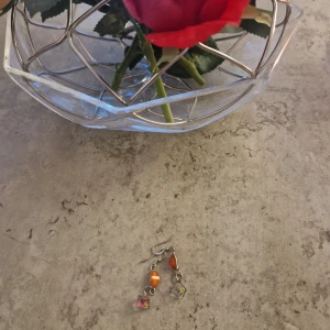 Färgglada hängande örhängen - Säljer ett par snygga örhängen med orange pärlor och glittrande kubformade detaljer i silverfärgad metall. Perfekta för dig som vill ha något unikt och färgstarkt till din stil.