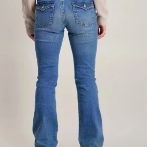 Blå bootcut jeans med fickdetaljer - Snygga blå jeans med knappfickor där bak. De är modernt lågmidjade (inte y2k lågmidjade) och är bootcut