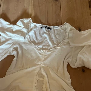 Vit blus från Gina Tricot - Supersöt vit blus från Gina. Är delad på mitten precis under brösten typ och har mycket spets. Tillverkad i bomull och jätte söt och romantisk. Aldrig använt.
