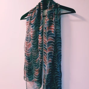 Färgglad mönstrad halsduk i silke - Snygg halsduk med vågigt mönster i blått, rött och vitt. Tunt och lätt material som ger en cool look och passar perfekt att slänga över axlarna. Ger outfiten en extra färgklick och känns riktigt trendig.  Helt & fint skick