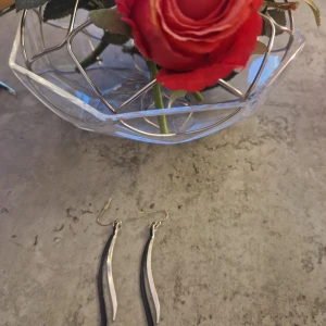 Silvriga böjda örhängen - Säljer ett par stilrena silvriga örhängen med böjd, avlång form. De har enkel krok och ger en modern, minimalistisk vibe. Perfekta för dig som gillar diskreta men snygga accessoarer.