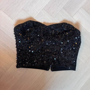 Svart paljettprydd tubtopp - Glittrig svart tubtopp täckt med paljetter. 