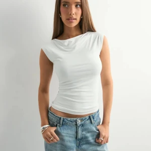 Vit ärmlös linnetopp - Snygg vit ärmlös topp med rund halsringning. Helt ny, aldrig använd. Säljer då jag har två stycken i samma storlek