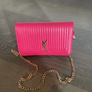 YSL rosa quiltad axelväska i skinn - Säljer en snygg rosa axelväska från YSL med klassisk kedjerem i guld och quiltad design. Väskan har magnetlås, flera fack inuti och ikonisk YSL-logga framtill. Perfekt storlek för det viktigaste och ger en poppig touch till din outfit. Härlig färg❤️