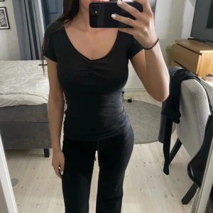 Svart topp med v-ringning - H&M storlek xs. Svart topp med korta ärmar och snygg v-ringning. Toppen en liten rynkdetalj vid bysten. 