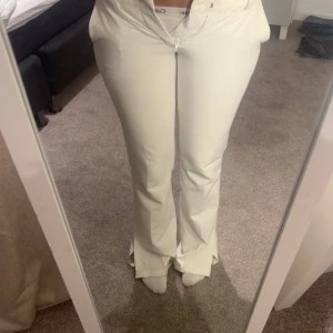 Vita bootcut byxor - Snygga vita bootcut byxor med låg midja och dragkedja. Perfekta för en stilren look. Rakt över midjan 14 innerbenslängd 30, kan gå ner i pris. Byxorna har en klassisk design med fickor och är tillverkade i ett bekvämt material. 