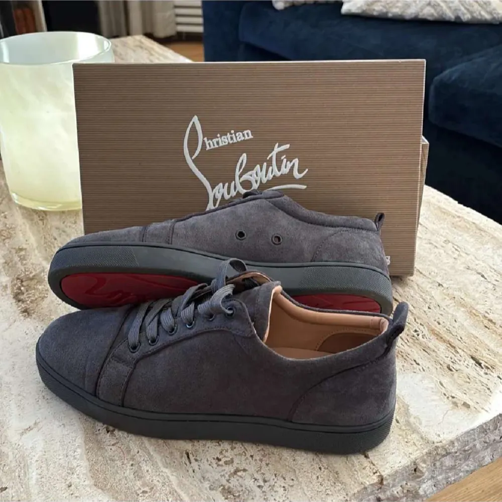 Snygga grå sneakers från Christian Louboutin i mocka med klassisk röd sula. Skorna har snörning och en stilren design som passar perfekt för en trendig look. Kvitto finns. Kengät.