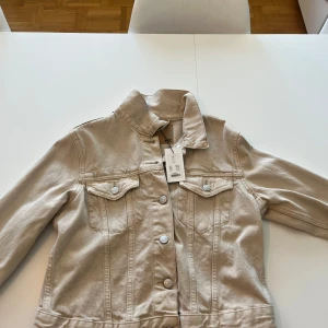Beige jeansjacka - Säljer en beige jeansjacka med knappar framtill. 