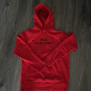 Röd peak performance hoodie i perfekt skick - Jag säljer min röda Peak Performance hoodie eftersom den är för liten. Hoodien är använd ett fåtal gånger och är i UTMÄRKT skick. 